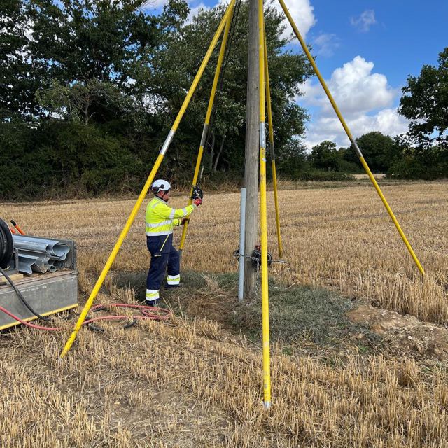 Linesman working on a pole held steady by yellow support stays